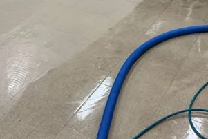 Tile floor being cleaned with a blue hose